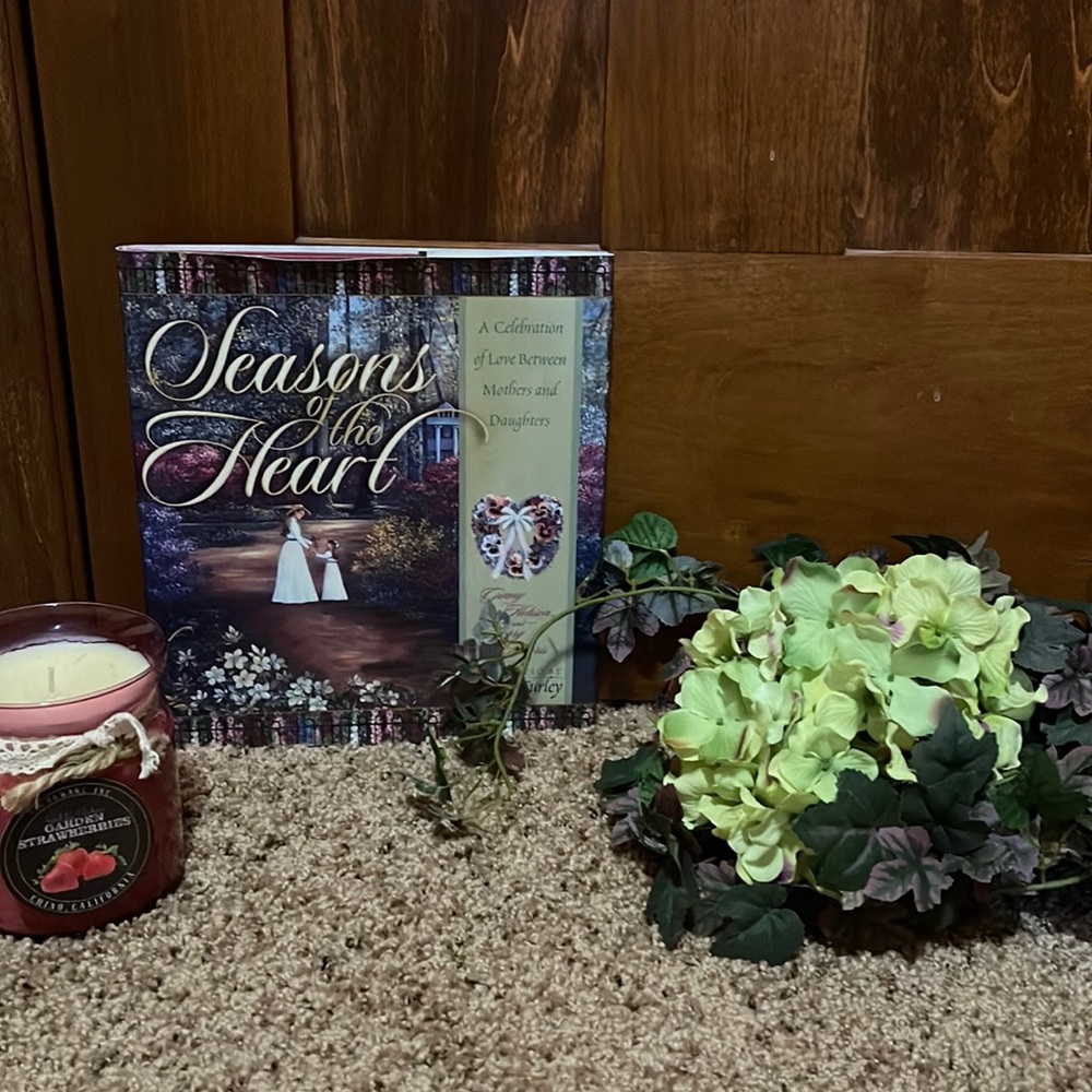 Candle, book, artificial flowers and greenery.